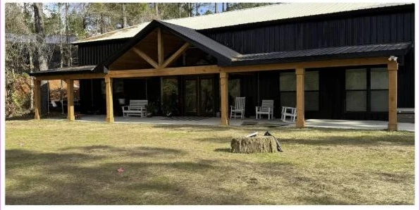 Finished black metal barndominium with timber post porch built by Keller Built Construction