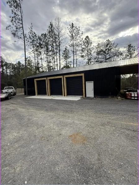 Black metal barndominium workshop with three roll-up doors, built by Keller Built Construction