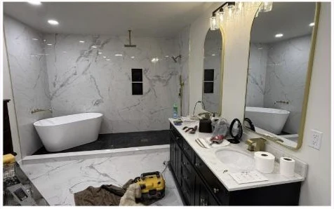 Finished master bathroom with marble tile, freestanding tub and gold fixtures