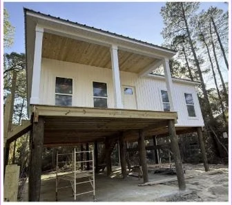 Completed elevated coastal home on pilings with white siding and a covered porch
