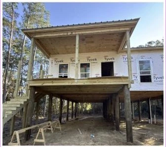 Elevated coastal home under construction on pilings with house wrap