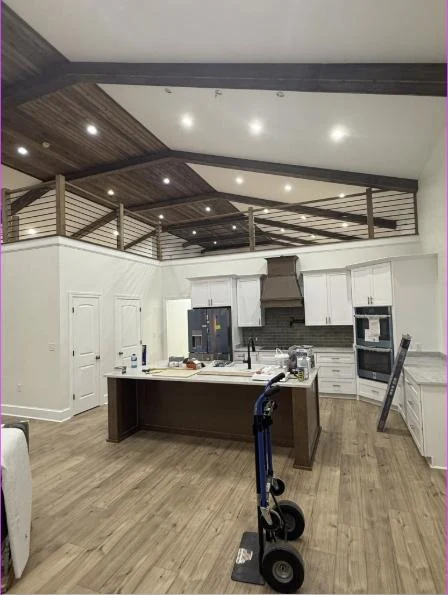 Kitchen with vaulted wood ceiling, exposed beams, white cabinets and an island