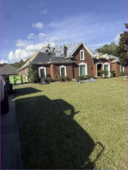 Crew replacing the roof on a brick home on a clear day
